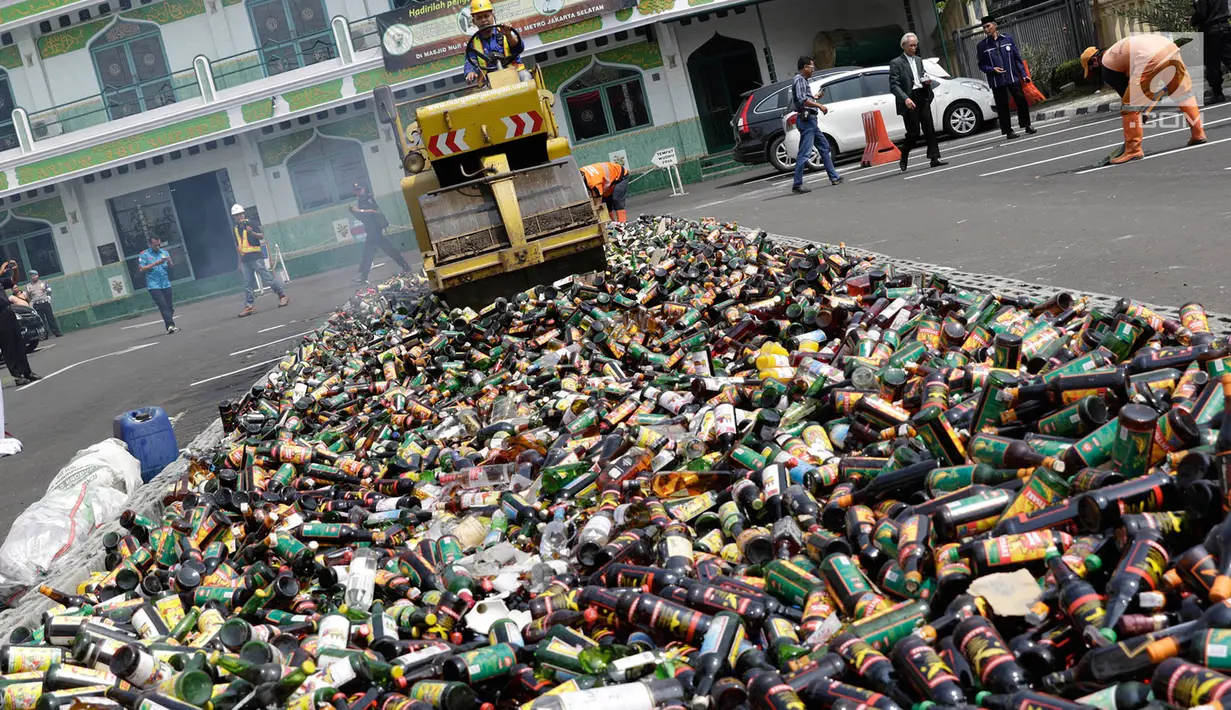 Petugas menggiling ribuan botol minuman keras (miras) menggunakan alat berat saat pemusnahan di halaman Mapolres Jakarta Selatan, Selasa (23/5). Ribuan botol ini disita dalam operasi yang dilakukan sejak Januari 2017. (Liputan6.com/Immanuel Antonius)