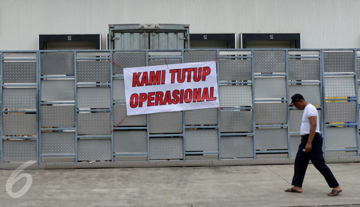 Warga melewati di spanduk 'Kami Tutup Operasional' di pabrik pengolahan ikan Pelabuhan Muara Baru, Jakarta, Senin (10/10). Mogok massal karena dibatasinya masa sewa di pelabuhan selama 5 tahun yang tadinya selama 20 tahun.  (Liputan6.com/Gempur M Surya)