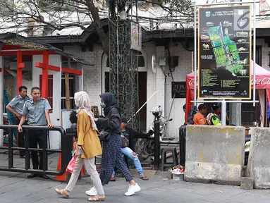 Pejalan kaki melintasi jalur masuk dan keluar Taman Fatahilah saat uji coba simulasi di kawasan Kota Tua, Jakarta, Selasa (23/4). Penataan akses tersebut dilakukan untuk memperlancar keluar masuknya pengunjung ke kawasan wisata tersebut. (Liputan6.com/Immanuel Antonius)