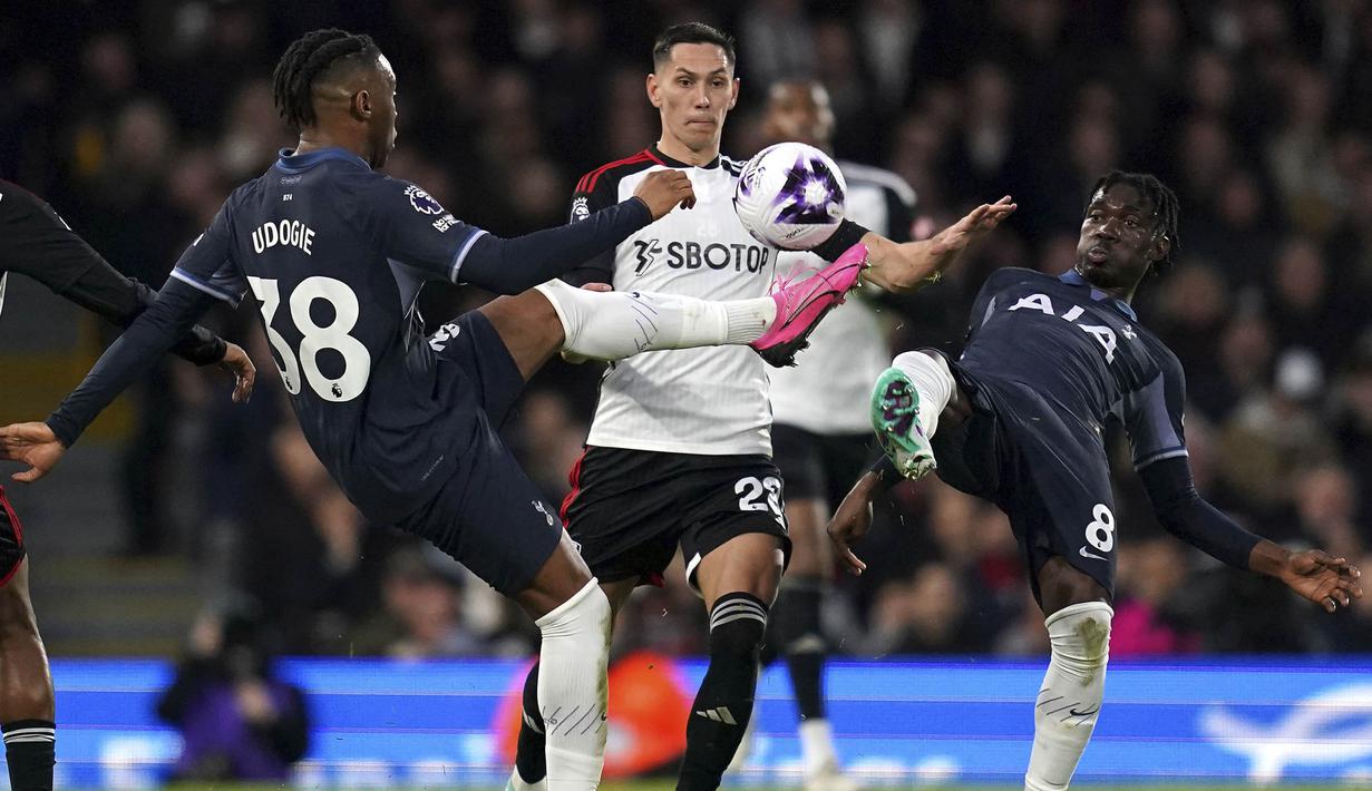 Pemain Tottenham Hotspur, Destiny Udogie dan Yves Bissouma berusaha mengadang pemain Fulham, Sasa Lukic, pada laga Liga Inggris di Stadion Craven Cottage, Minggu (17/3/2024). (Adam Davy/PA via AP)