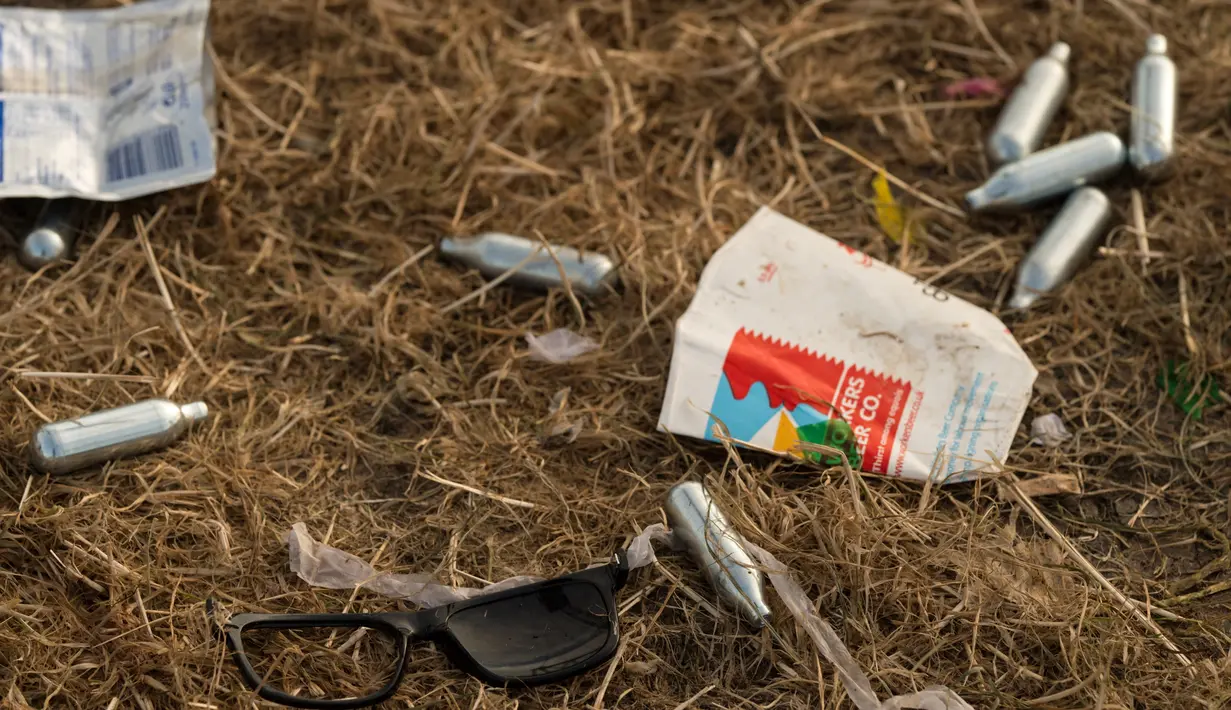 Tabung oksida nitrat tergeletak dekat Pyramid Stage pada akhir Festival Glastonbury di arena Worthy Farm, Inggris, 26 Juni 2017. Penyelenggaraan festival musik terbesar di dunia itu menyisakan sampah yang berserakan di seluruh arena. (OLI SCARFF/AFP)