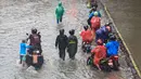 Berdasarkan laporan petugas, banjir dipicu oleh curah hujan yang tinggi dalam waktu cukup lama. Selain itu, luapan Kali Krukut turut memperparah genangan di sejumlah kawasan yang berada di sekitar aliran sungai tersebut. Tampak dalam foto, pengendara dan pejalan kaki melintasi banjir yang menggenangi Jalan Jembatan Tiga Raya, Jakarta Utara, Senin (12/1/2026). (merdeka.com/Arie Basuki)