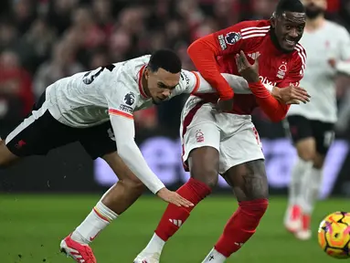 Gelandang Nottingham Forest, Callum Hudson-Odoi (kanan) berebut bola dengan pemain Liverpool, Trent Alexander-Arnold selama pertandingan pekan ke-21 Premier League 2024/2025 di The City Ground, Nottingham, Inggris, pada Selasa 14 Januari 2025 waktu setempat atau Rabu (15/1/2025) dini hari WIB. (Paul ELLIS/AFP)