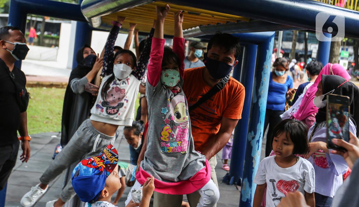 Anak-anak didampingi orang tua mereka bermain di Taman Puring, Jakarta, Minggu (9/1/2022). Di tengah ancaman penyebaran covid-19 varian Omicron dan pemberlakukan PPKM level 2, masyarakat tetap melakukan aktivitas pada akhir pekan di luar rumah. (Liputan6.com/Johan Tallo)