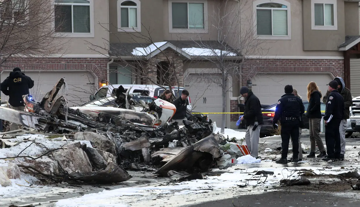 Tim penyelamat melihat puing-puing pesawat pribadi yang jatuh di kawasan perumahan Roy, Utah, Amerika Serikat, Rabu (15/1/2020). Pesawat menabrak atap rumah sebelum akhirnya menghantam tanah dan terbakar. (Steve Griffin/The Deseret News via AP)