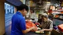 Nenek Leong Yuet Meng (90) dan putranya Michael Tang (66) bersiap untuk membuka warungya di Singapura (22/2). Leong Yuet Meng masih menjalankan usaha warung mie pangsit, meski berusia sudah menginjak 90 tahun. (Reuters/Edgar Su)
