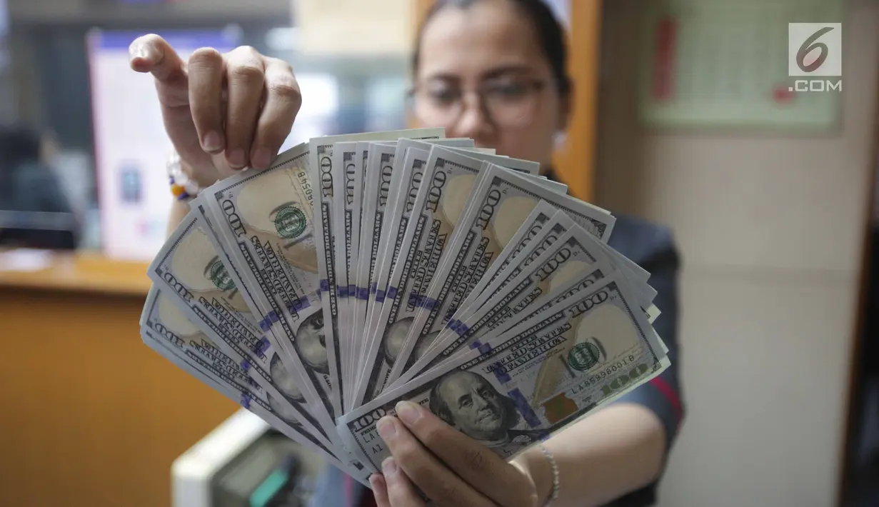 Teller menunjukkan mata uang dolar di Jakarta, Jumat (2/2). Dengan nilai tersebut posisi nilai tukar rupiah sudah masuk level undervalued, atau telah keluar dari level fundamentalnya. (Liputan6.com/Angga Yuniar)