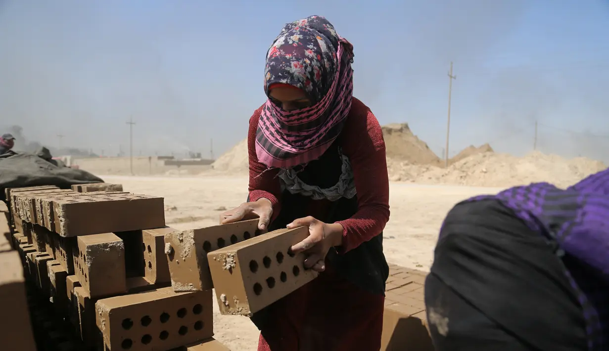 Zahra Ali (19) bekerja di pabrik batu bata di sebuah pabrik batu bata di pinggiran tenggara Baghdad Nahrawan, Irak, Kamis (24/5/2021). Ali bekerja 12 jam sehari dengan upah sekitar USD$ 15. (AP Photo/Hadi Mizban )