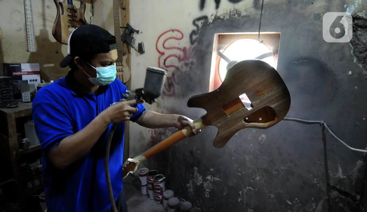 Pekerja menyelesaikan pembuatan gitar listrik Syukey Instrumen di kawasan Ciputat Timur, Tangerang Selatan, Banten, Selasa (26/10/2021). Pasca-PPKM, produksi gitar listrik mulai menggeliat kembali setelah selama dua tahun vakum dan hanya melayani service gitar. (merdeka.com/Arie Basuki)