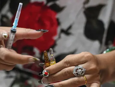  Gambar yang diambil pada 20 Februari 2017 menunjukkan Jessica Nguyen (31) mempersiapkan dosis suntik hormon di tokonya, Ho Chi Minh, Vietnam (30/3). Vietnam merupakan salah satu negara yang menolak keras transgender. (AFP Photo/Hoang Dinh Nam)