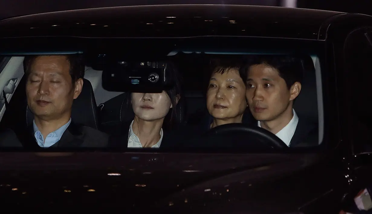 Mantan Presiden Korea Selatan, Park Geun-hye bersama penyidik meninggalkan kantor kejaksaan menuju rumah tahanan di Seoul selatan, Jumat (31/3). Park ditahan atas tuduhan menerima suap dan penyalahgunaan wewenang. (Chung Sung-Jun/Pool photo via AP)