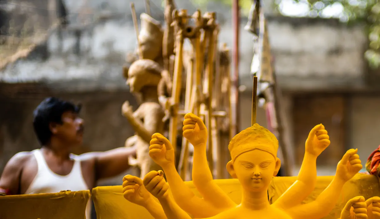 Seorang perajin membuat patung dewi Durga menjelang festival 'Durga Puja' di sebuah workshop di New Delhi, India, Rabu (14/10/2020). Durga Puja merupakan festival tahunan di Asia Selatan untuk memuja dewi Durga dari agama Hindu. (Photo by Jewel SAMAD / AFP)