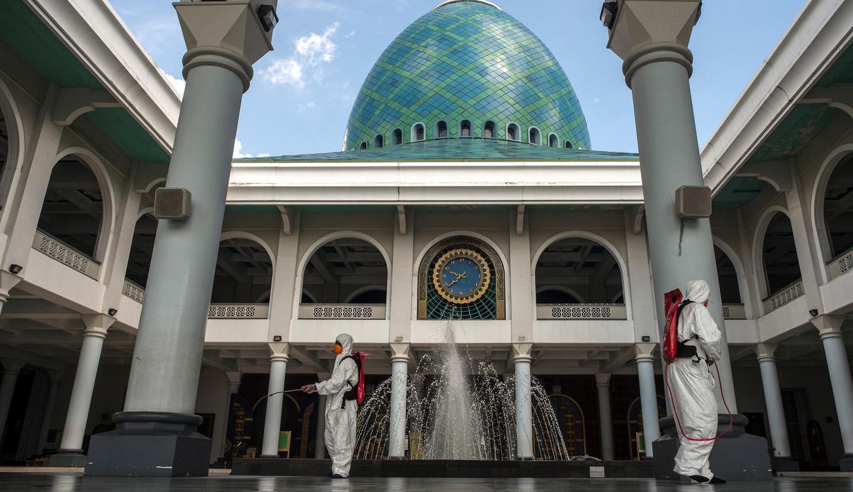 Pekerja dari otoritas penanggulangan bencana setempat menyemprotkan desinfektan di sebuah masjid di Surabaya, Jawa Timur, Selasa (17/3/2020). Kegiatan tersebut dilakukan untuk mencegah penyebaran Virus Corona COVID-19. (Photo by Juni Kriswanto / AFP)