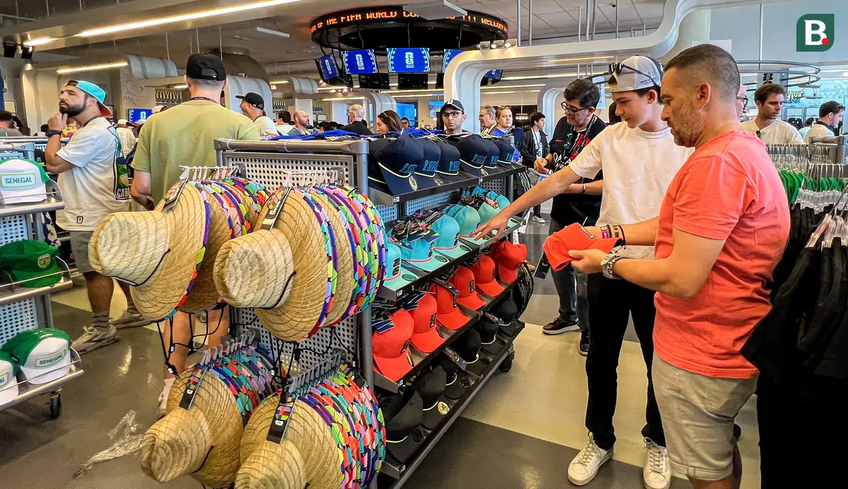 Suporter memilih topi dan berbagai aksesori resmi Piala Dunia 2026 di FIFA Store, MetLife Stadium, East Rutherford, New Jersey, Amerika Serikat, menjelang laga fase grup Prancis melawan Senegal. Beragam merchandise resmi menjadi buruan penggemar dari berbagai negara. (KLY Sports/Hery Kurniawan)