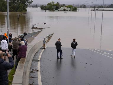 Orang-orang memandangi Jembatan Windsor yang banjir di Windsor di pinggiran Sydney, Australia, Selasa (5/6/2022). Ratusan rumah terendam di dalam dan sekitar kota terbesar Australia itu dalam keadaan darurat banjir yang berdampak pada 50.000 orang, kata para pejabat. (AP Photo/Mark Baker)