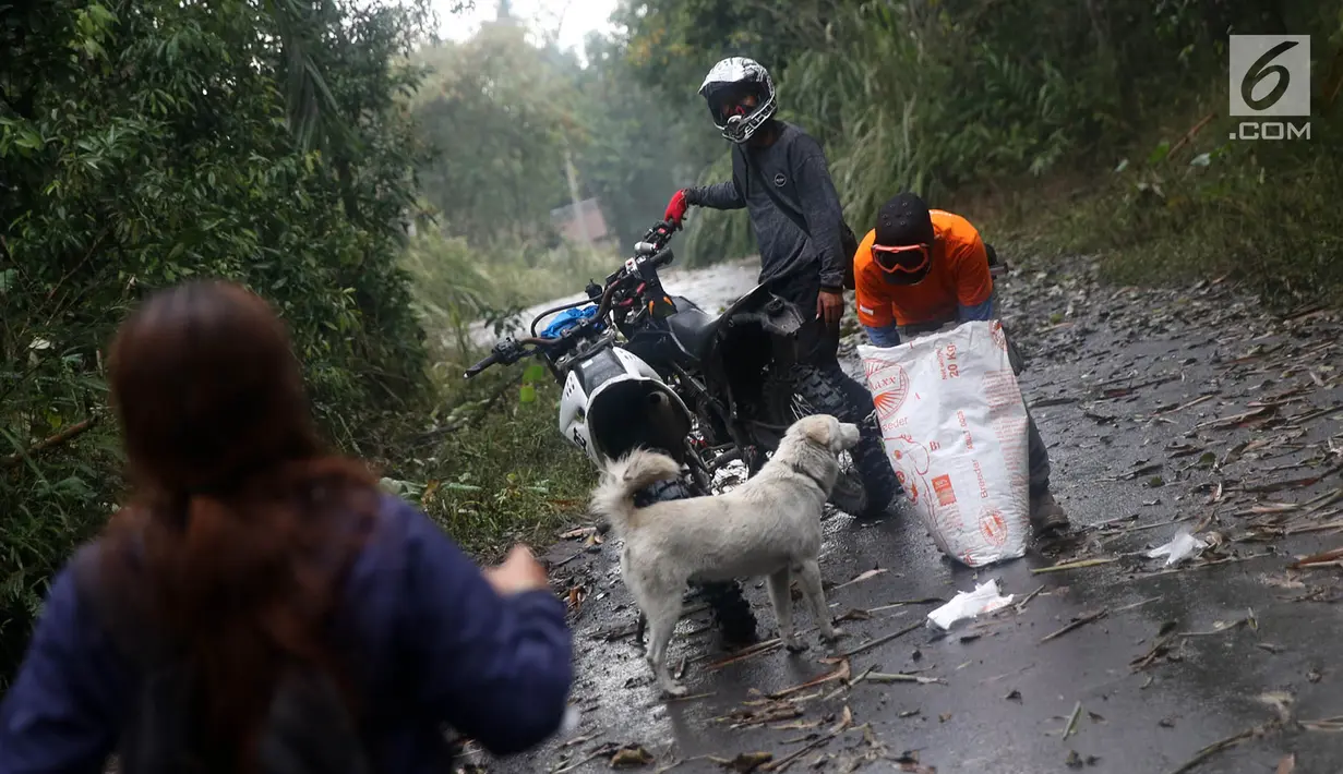 Relawan Bali Rumah Singgah Satwa memberi makan anjing yang ditinggalkan pengungsi di Dusun Sogra, Desa Sebudi, Karangasem, Bali, Minggu (3/12). (Liputan6.com/Immanuel Antonius)