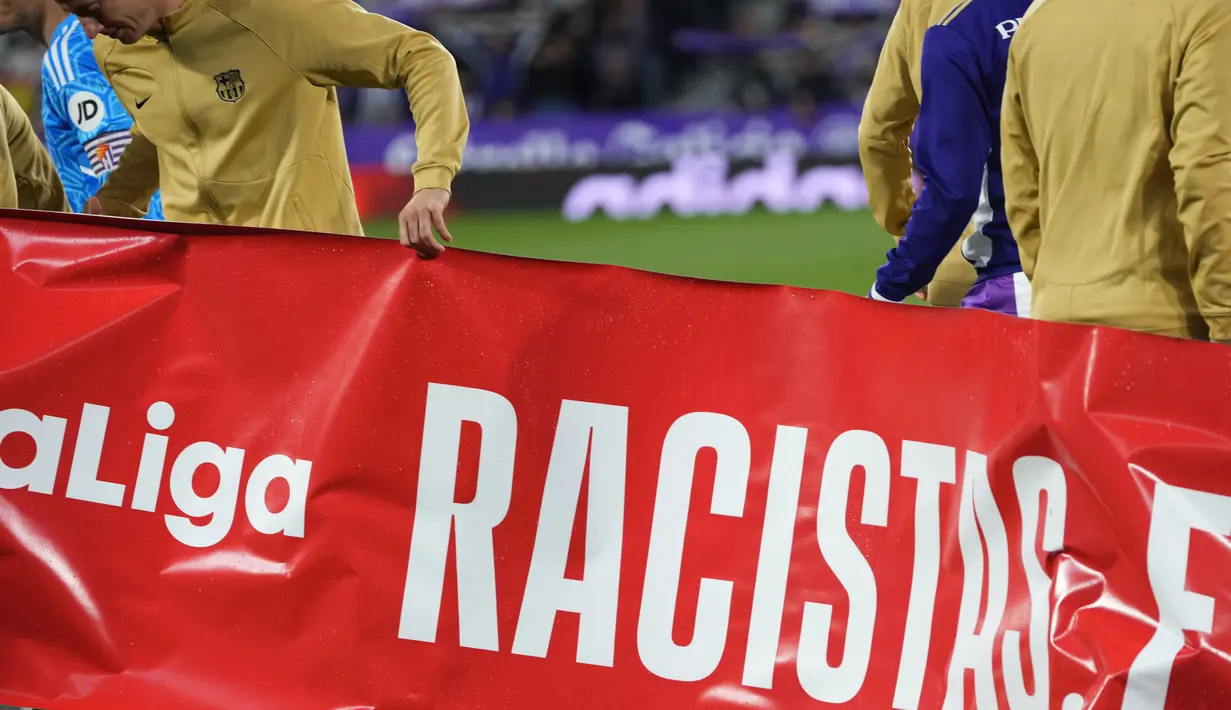 Para pemain Barcelona dan Valladolid bersama ofisial pertandingan berpose dengan spanduk ini sebelum laga LaLiga mereka. (AP Photo/Manu Fernandez)