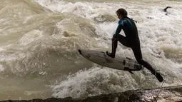 Peselancar bermain "surfing" di sungai buatan Eisbach yang terletak di English Garden Munich, Jerman pada 28 Mei 2019. Eisbach merupakan salah satu tempat berselancar sungai yang paling populer di kota Munich. (Photo by Peter Kneffel/dpa/AFP)