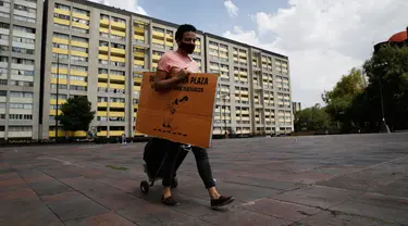 Percibald Garcia, pembaca cerita untuk anak-anak, menarik pengeras suara saat akan mendongeng di antara gedung-gedung di Mexico City pada 18 Juli 2020. Di tengah lockdown, Garcia hampir setiap hari mendatangi kompleks perumahan Tlatelolco untuk bercerita menghibur anak-anak. (AP/Marco Ugarte)