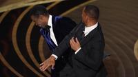 Will Smith (kanan) memukul presenter Chris Rock di atas panggung Piala Oscar 2022 saat mempersembahkan penghargaan untuk film dokumenter terbaik di Dolby Theatre, Minggu (27/3/2022). Will Smith merasa lawakan sang komedian terkait istrinya, Jada Pinkett Smith keterlaluan. (AP Photo/Chris Pizzello)