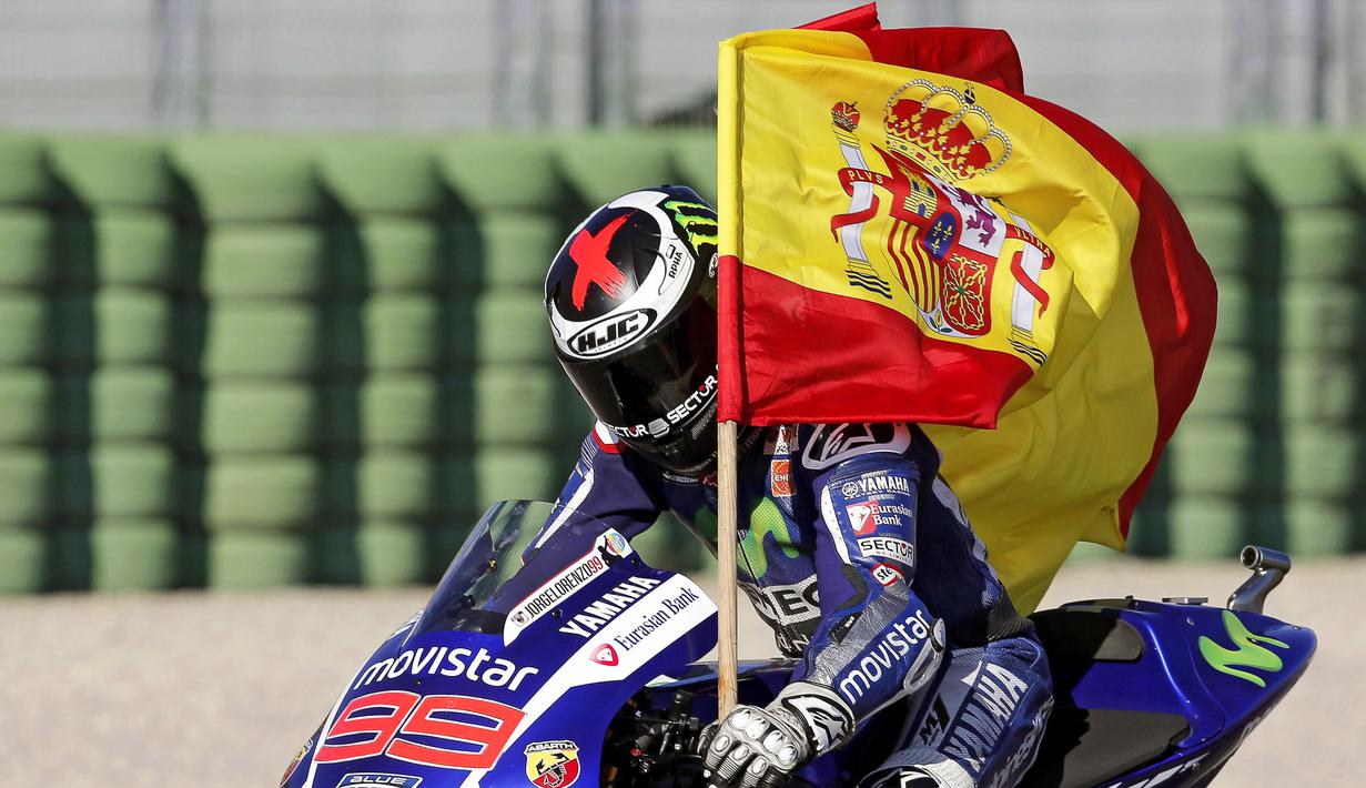 Jorge Lorenzo merayakan kemenangannya dengan membawa bendera Spanyol dalam MotoGP Valencia di Sirkuit Ricardo Tormo, Valencia, Spanyol, (8/11/2015). (EPA/Manuel Bruque)