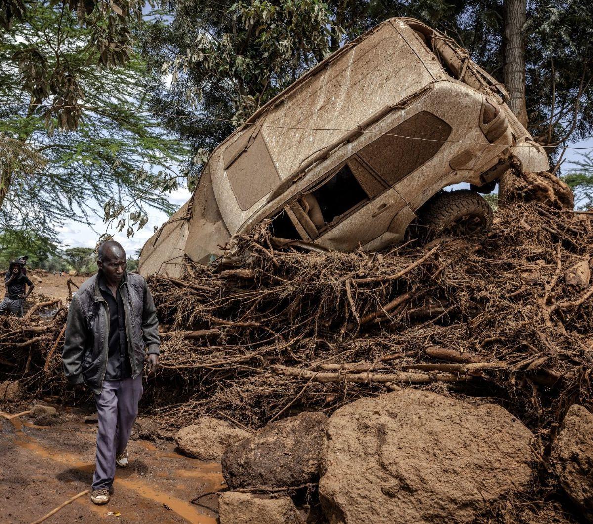 Warga berjalan di dekat sebuah mobil yang tersapu banjir bandang di Desa Kamuchiri, Kota Mai Mahiu, Kenya, Senin (29/4/2024). Terjangan banjir bandang dan tanah longsor di Mai Mahiu, yang menyapu rumah-rumah dan mobil, menewaskan sedikitnya 45 orang dan m