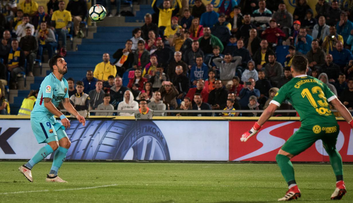 Pemain Barcelona, Luis Suarez melihat bola di depan kiper Las Palmas, Leandro Chichizola pada jornada ke-26 La Liga 2017-2018 di Estadio Gran Canaria, Kamis (1/3). Barcelona hanya memetik hasil imbang 1-1 dari tim papan bawah klasemen (DESIREE MARTIN/AFP)