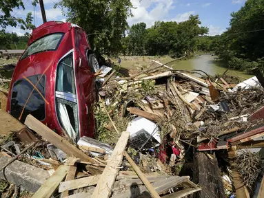 Sebuah mobil termasuk di antara puing-puing yang terdampar di jembatan di atas sungai di Waverly, Tennessee, Minggu (22/8/2021). Banjir parah yang melanda Middle Tennessee, AS, menyebabkan sedikitnya 22 orang tewas, sementara sekitar 50 orang lainnya dilaporkan masih hilang. (AP Photo/Mark Humphrey