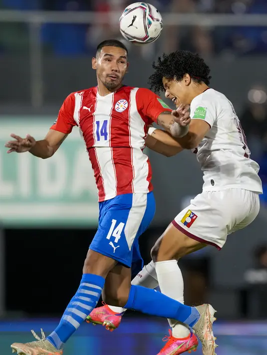 Bek Paraguay, Hector Martinez dan gelandang Venezuela, Eduard Bello melakukan sundulan dalam lanjutan Kualifikasi Piala Dunia 2022 zona Conmebol di Estadio Defensores del Chaco, Asuncion, Jumat (10/9/2021) pagi. Paraguay memetik kemenangan tipis 2-1 atas Venezuela. (AP/Jorge Saenz)