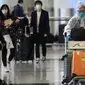 Penumpang mengenakan pakaian pelindung saat tiba di Bandara Internasional Hong Kong, Hong Kong (19/3/2020). Covid-19 yang menginfeksi lebih dari 200.000 orang terus menimbulkan kekhawatiran. (AFP/Anthony Wallace)