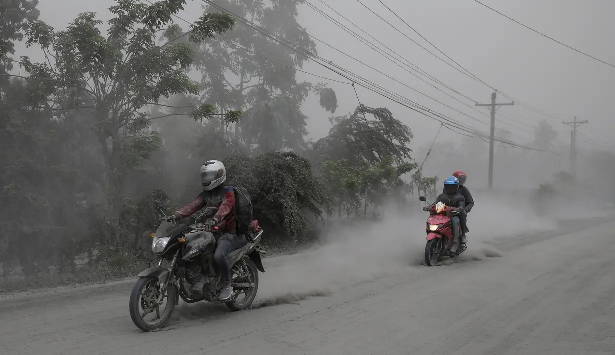 Pengendara motor melintasi jalan yang tertutup abu vulkanik dari gunung Taal untuk mengungsi di Lemery, provinsi Batangas, Filipina, Senin (13/11/2020). Erupsi gunung Taal memaksa puluhan ribu orang mengungsi serta membuat sekolah-sekolah dan toko di Manila tutup. (AP/Aaron Favila)
