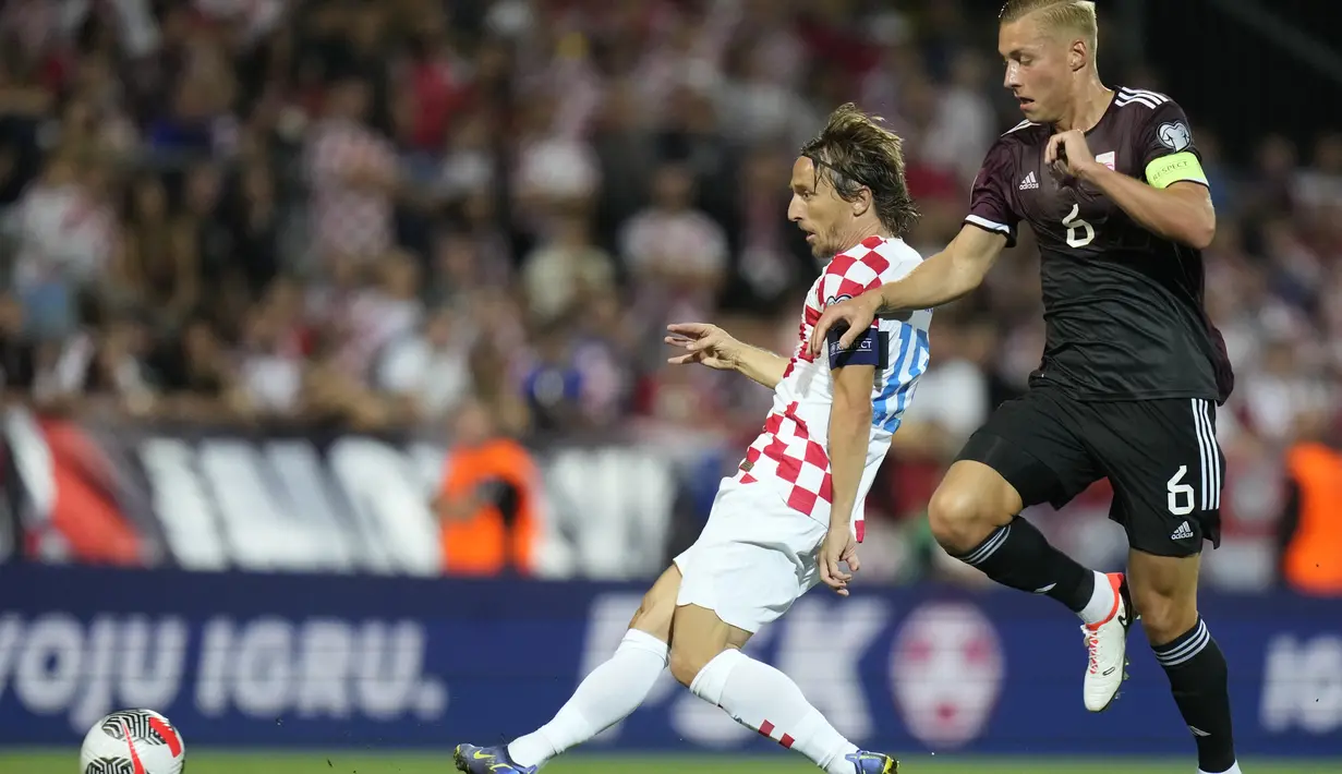 Gelandang Kroasia Luka Modric berebut bola dengan gelandang Latvia Kristers Tobers dalam laga Grup D Kualifikasi Euro 2024 di stadion Rujevica di Rijeka, Sabtu (9/9/2023) dini hari WIB. (AP Photo/Darko Bandic)