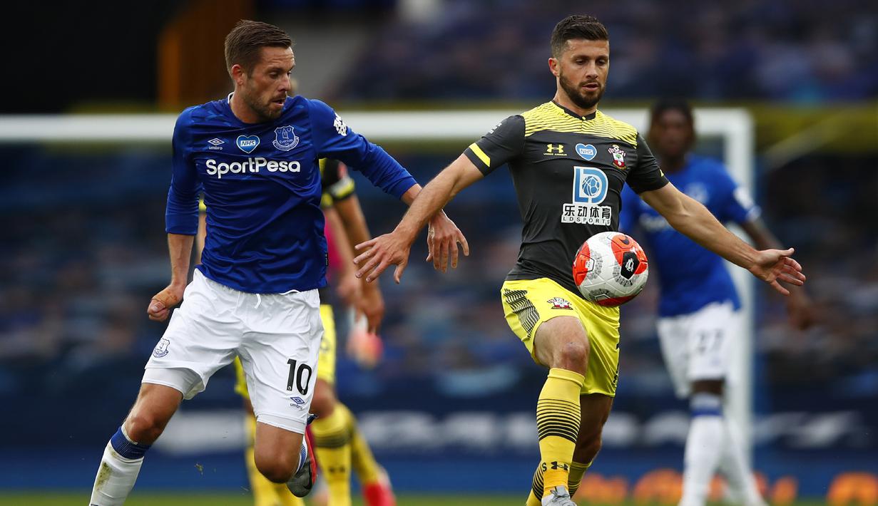 Penyerang Southampton, Shane Long, berebut bola dengan gelandang Everton, Gylfi Sigurdsson, pada laga lanjutan Premier League pekan ke-34 di Goodison Park, Jumat (10/7/2020) dini hari WIB. Everton bermain imbang 1-1 atas Southampton. (Clive Brunskill/Pool via AP)