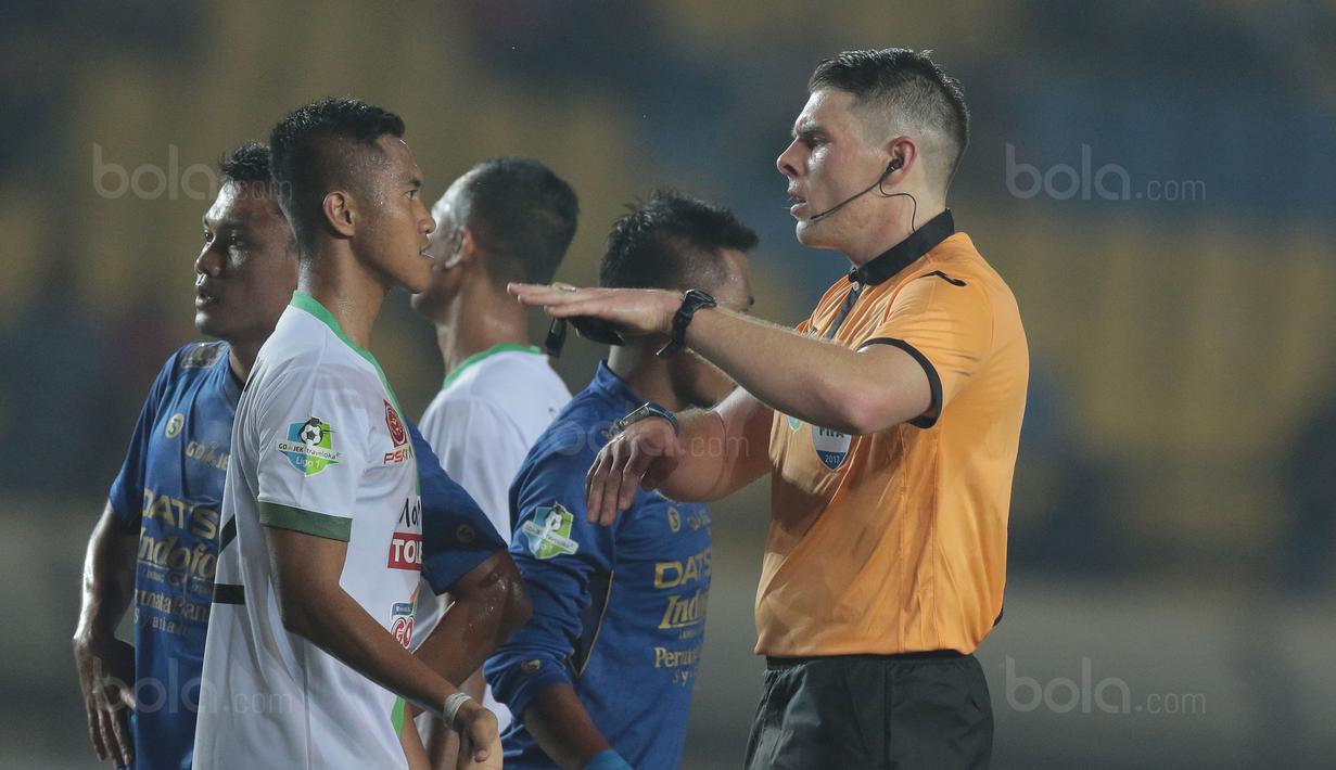 Wasit Evan Shaun Robert memberikan mencoba memberikan penjelasan kepada pemain PS TNI, Sansan Husaeni saat laga melawan Persib Bandung pada lanjutan Liga 1 2017 di Stadion Si Jalak Harupat, Sabtu (05/8/2017). (Bola.com/Nicklas Hanoatubun)