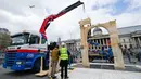 Petugas mengamati alat berat yang meletakkan lengkungan Palmyra berukuran seperti aslinya, sehari sebelum diresmikan di Trafalgar Square, pusat kota London, Senin (18/4). Replika tersebut sebagai simbol perlawanan terhadap terorisme. (Leon Neal/AFP)