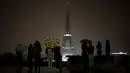 Pengunjung berkumpul di alun-alun Trocadero ketika lampu Menara Eiffel dipadamkan di Paris, Senin (2/10). Pemadaman lampu menara yang menjadi ikon Negara Prancis ini sebagai bentuk penghormatan untuk korban penembakan di Las Vegas. (AP/Kamil Zihnioglu)