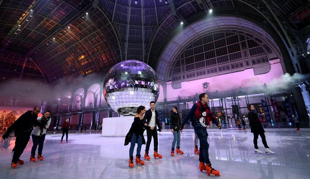 Orang-orang berseluncur di arena ice skating di bawah kubah kaca mewah legendaris, Grand Palais, Paris, Selasa (17/12/2019). Arena ice skating musiman ini menjadi yang terbesar di Prancis, dan satu magnet wisata sepanjang tahun. (Photo by Thomas SAMSON / AFP)