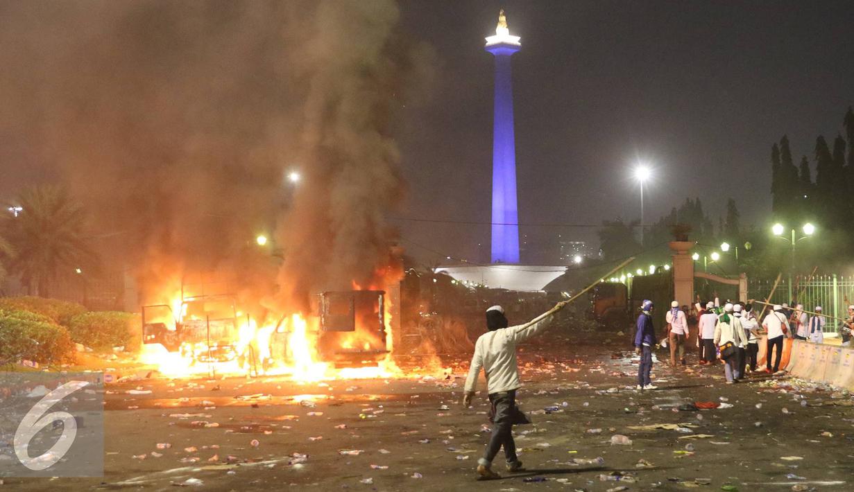 Sejumlah mobil dibakar pendemo saat terjadi bentrok dengan polisi di kawasan Monas, Jakarta, Jumat (4/11). Diduga bentrok terjadi saat massa HMI menyerang polisi dan polisi membalasnya dengan melempar gas air mata. (Liputan6.com/Immanuel Antonius)