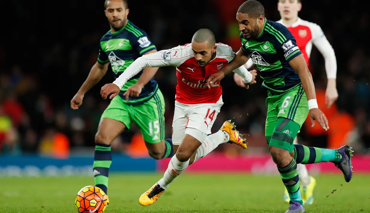 Gelandang Arsenal, Theo Walcott (tengah) berusaha melewati dua pemain Swansea City pada lanjutan liga Inggris di Stadion Emirates (2/3). Swansea menang atas Arsenal dengan skor 2-1. (Reuters/John Sibley)