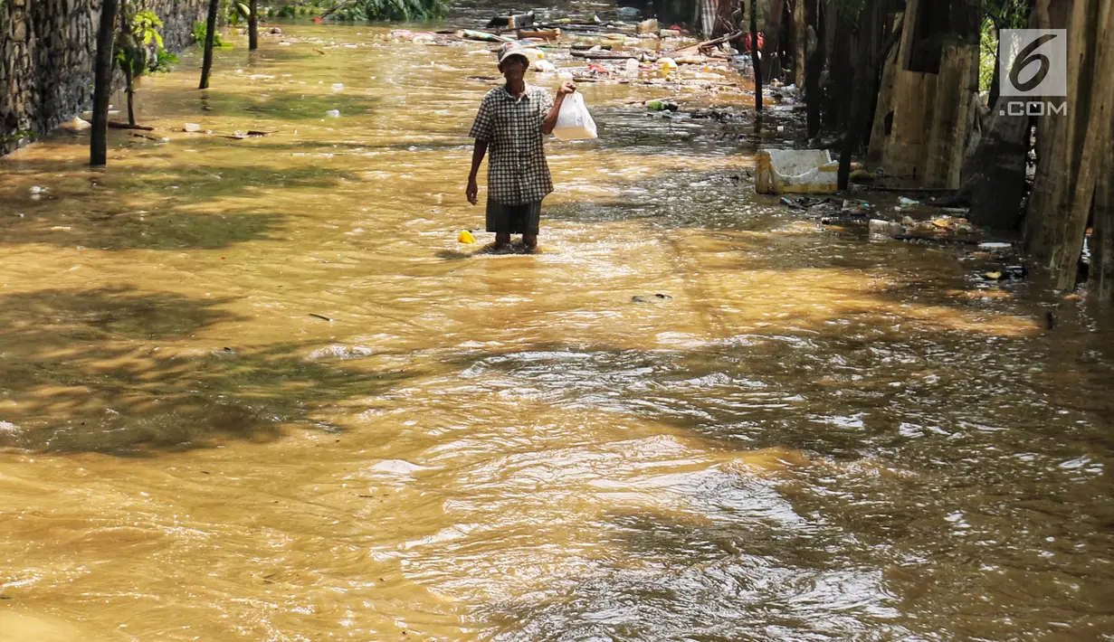 Warga melintasi banjir yang melanda kawasan bantaran kali Cisadane, Tangerang, Jumat (26/4). Banjir kiriman setinggi 2 meter sempat melanda kawasan akibat curah hujan yang tinggi di bogor membuat derasnya air mengalir jauh sampai ke tempat ini. (Liputan6.com/Johan Tallo)