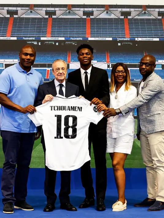 <p>Pemain baru Real Madrid, Aurelien Tchouameni (tengah) berpose dengan jersey Real Madrid saat perkenalan resminya di tempat latihan klub di Madrid, Spanyol, Selasa (14/6/2022). Pemain berusia 22 tahun itu akan menggunakan nomor punggung 18 pada musim 2022-2023. (twitter.com/realmadrid)</p>