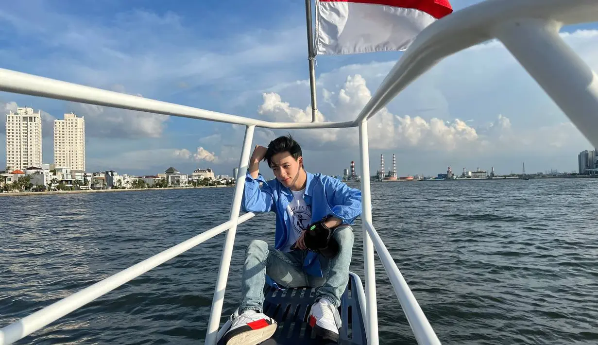 Tampil mengganteng dengan baju biru-putih, gaya Jeno berpose bareng bendera Merah Putih bak sedang Agustusan. (Twitter/@NCTsmtown_DREAM).