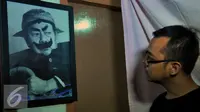 Seorang kerabat memandangi lukisan wajah Almarhum Pak Raden atau Suyadi di rumah duka Petamburan III, Jakarta (30/10/2015). Pak Raden menghembuskan napas terakhirnya di Rumah Sakit Pelni. (Liputan6.com/Faisal R Syam)