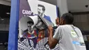 Pekerja melepas poster yang menampilkan pemain depan Argentina, Lionel Messi di pintu masuk Stadion Camp Nou, Barcelona pada Selasa, 10 Agustus 2021. Lionel Messi resmi meninggalkan Barcelona akibat masalah finansial klub dan peraturan dari Liga Spanyol. (AFP/Pau Barrena)