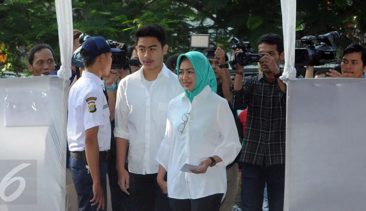 Calon Walikota Tangerang Selatan, Airin Rachmi Diany (kanan) bersama putra pertama, TB Ghifari Wardana (kiri) tiba di TPS 17 Serpong Utara, Tangerang Selatan, Banten, untuk menggunakan hak pilihnya, Rabu (9/12). (Liputan6.com/Helmi Afandi)