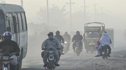 Pengendara melintas di sepanjang jalan di tengah kondisi kabut asap di Lahore, Pakistan (23/11/2021). Kondisi kabut asap yang memburuk membuat Lembaga pendidikan, kantor swasta tutup selama tiga hari seminggu di Lahore. (AFP/Arif Ali)