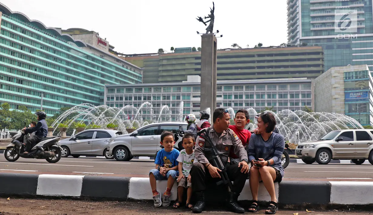 Brigpol Inardi Susanto asal Polres Tarakan, yang sudah sebulan bertugas di Jakarta, bersenda gurau dengan adik dan keponakan yang sengaja mengunjunginya di kawasan Bundaran HI, Minggu (9/6/2019). Sejumlah aparat kepolisian banyak yang tetap bertugas saat Lebaran 2019. (Liputan6.com/Herman Zakharia)