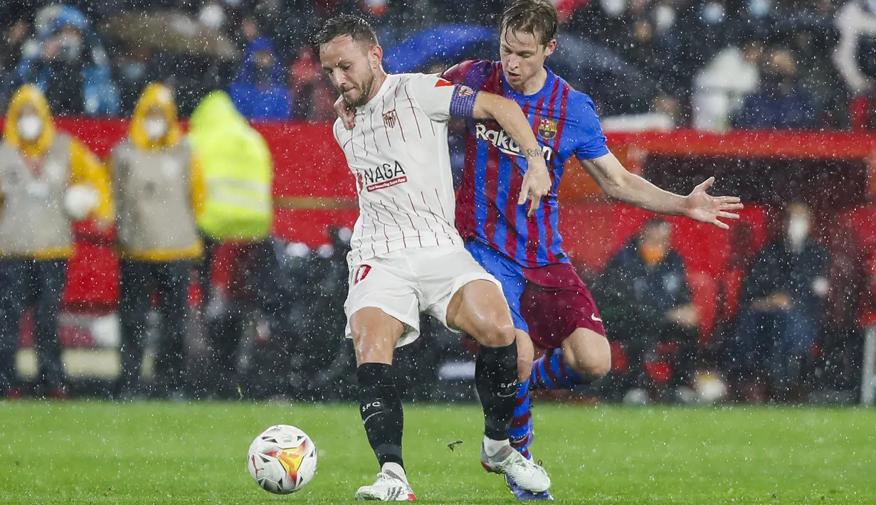 Gelandang Sevilla, Ivan Rakitic berusaha mengontrol bola dari kawalan gelandang Barcelona, Frenkie de Jong pada pertandingan La Liga Spanyol di stadion Ramon Sanchez-Pizjuan, Spanyol, Rabu (22/12/2021). Sevilla kini berada di urutan kedua dengan 38 poin. (AP Photo/Angel Fernandez)
