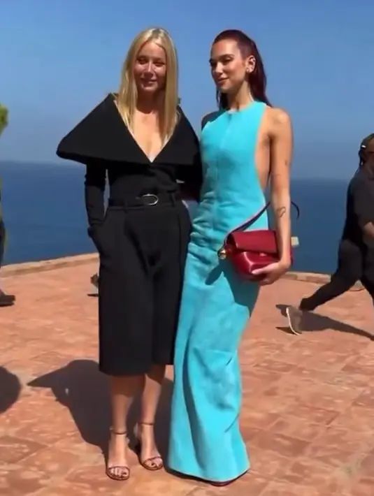 Dua Lipa menyelesaikan tampilannya dengan tas dan sandal heels berwarna merah [@dualipa]