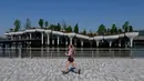 Seorang pelari berlari melewati 'Pulau Kecil', taman umum baru dan gratis di Hudson River Park, New York City, Amerika Serikat, 21 Mei 2021. Taman yang diresmikan pada 21 Mei 2021 tersebut menghabiskan dana sebesar USD USD 260 juta. (Angela Weiss/AFP)